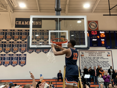 Naperville North guard Zeke Williams cuts the net off after regional championship victory