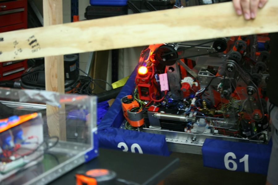 The team robot hangs from the pipe while the team discusses and collaborates.