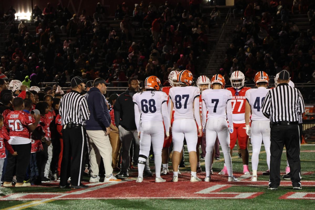 Huskie and Viking players meet at midfield before the game for the coin flip.