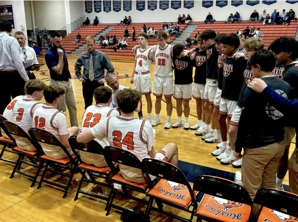 Head Coach Gene Nolan describes the next play to the Naperville North varsity boys basketball team.
