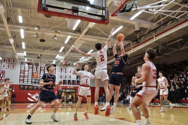 Will Harvey (22) shoots the ball over a Redhawk defender’s hand.