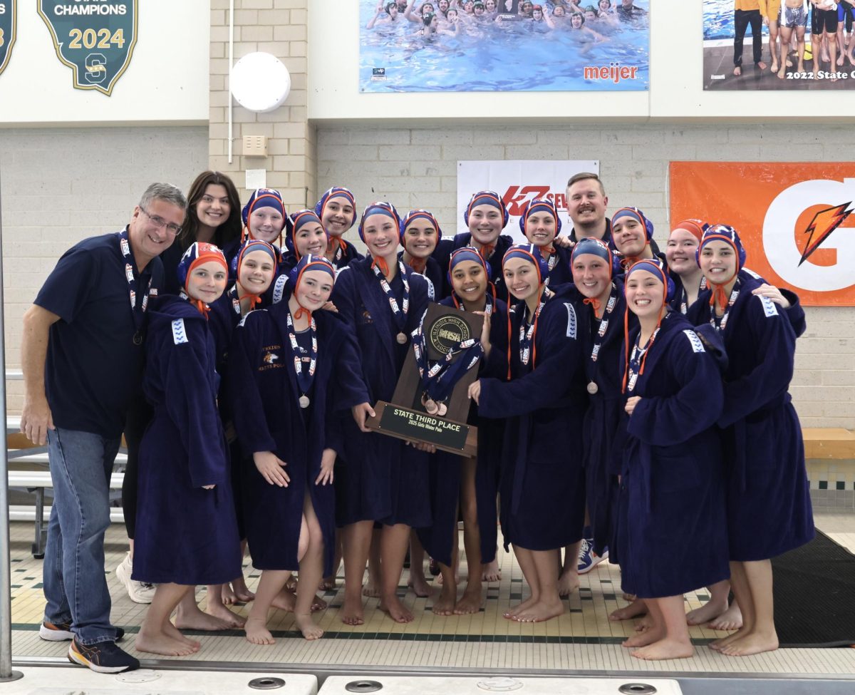 The players and their coaches smile with their third-place state trophy.