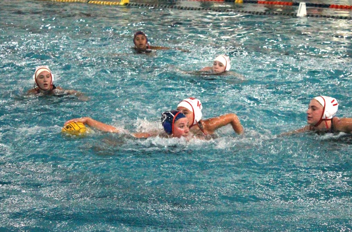 Payton Schrier (15) protects the ball as she moves around a Redhawk defender.