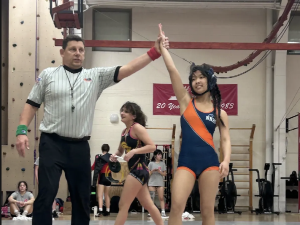 Referee holds KeYi Wang's arm up, signaling her win. Photo courtesy of sibling of Wang's teammate.