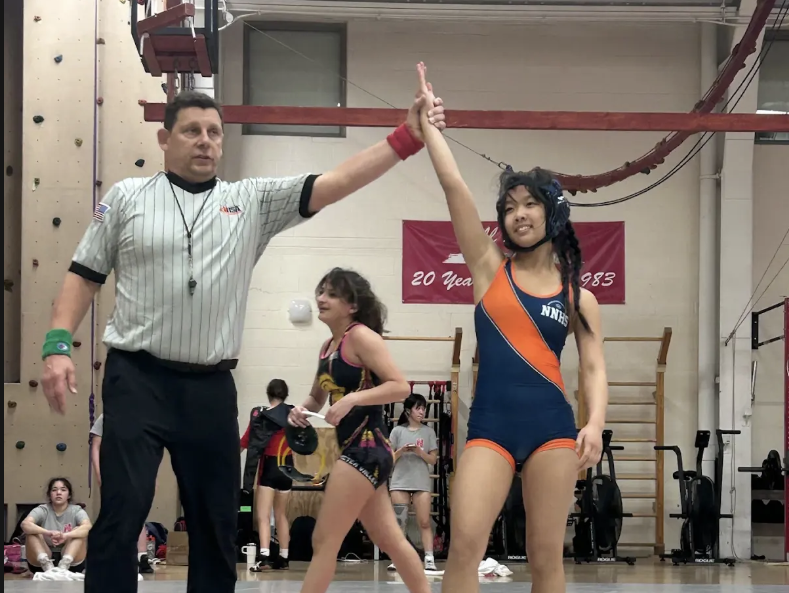 Referee holds KeYi Wang's arm up, signaling her win. Photo courtesy of sibling of Wang's teammate.